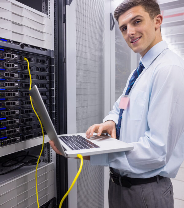 Portrait of a technician using laptop while analysing server in large data center